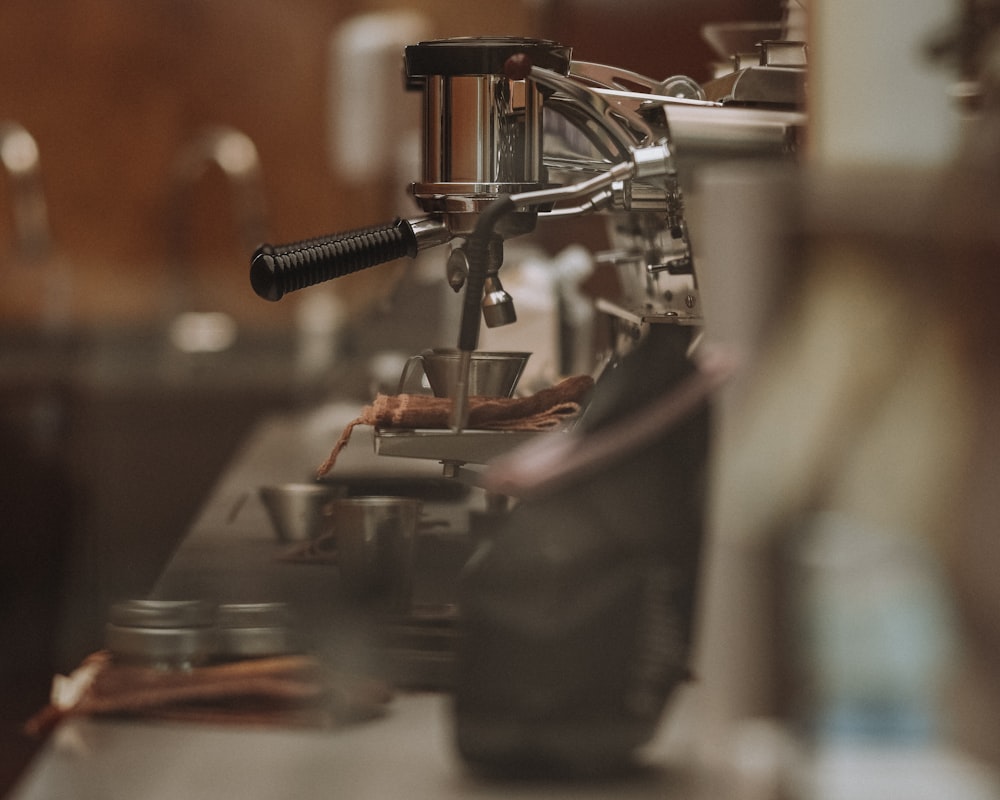 A chrome lever espresso machine on the bar, portafilter locked in and a shot glass waiting underneath.
